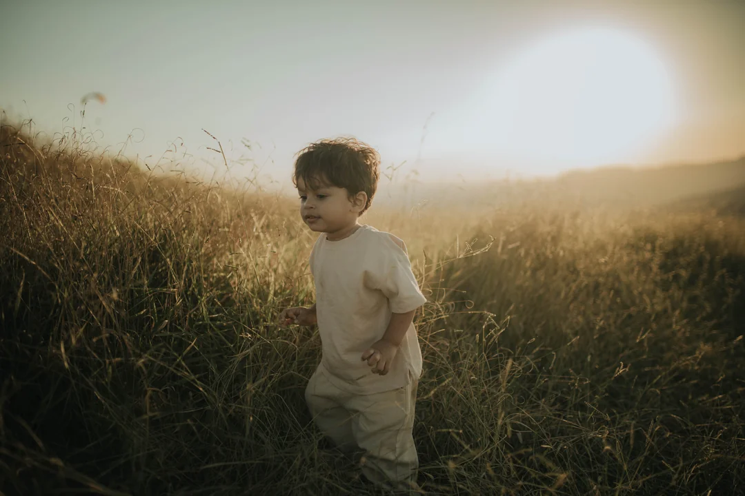 Menino brincando no campo ao pôr do sol